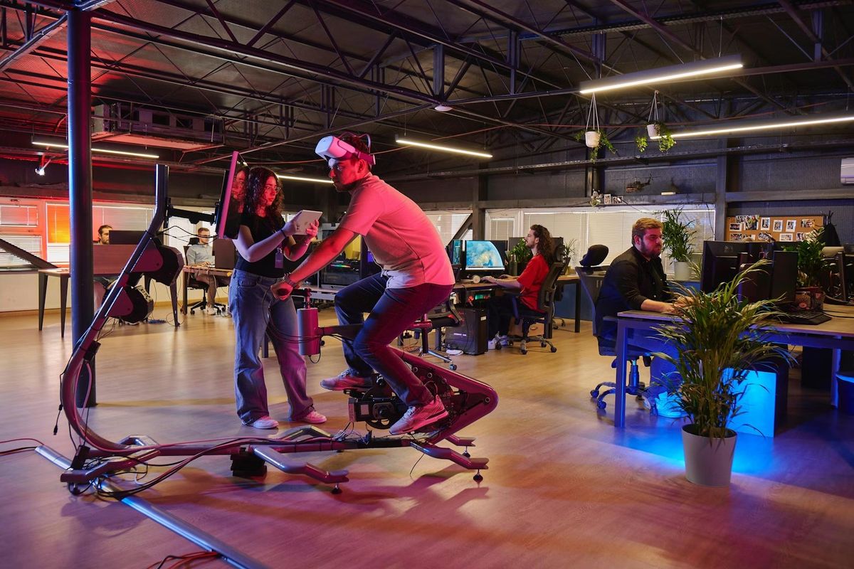 Person on Voyager Metabike in modern office, coworkers at desks.