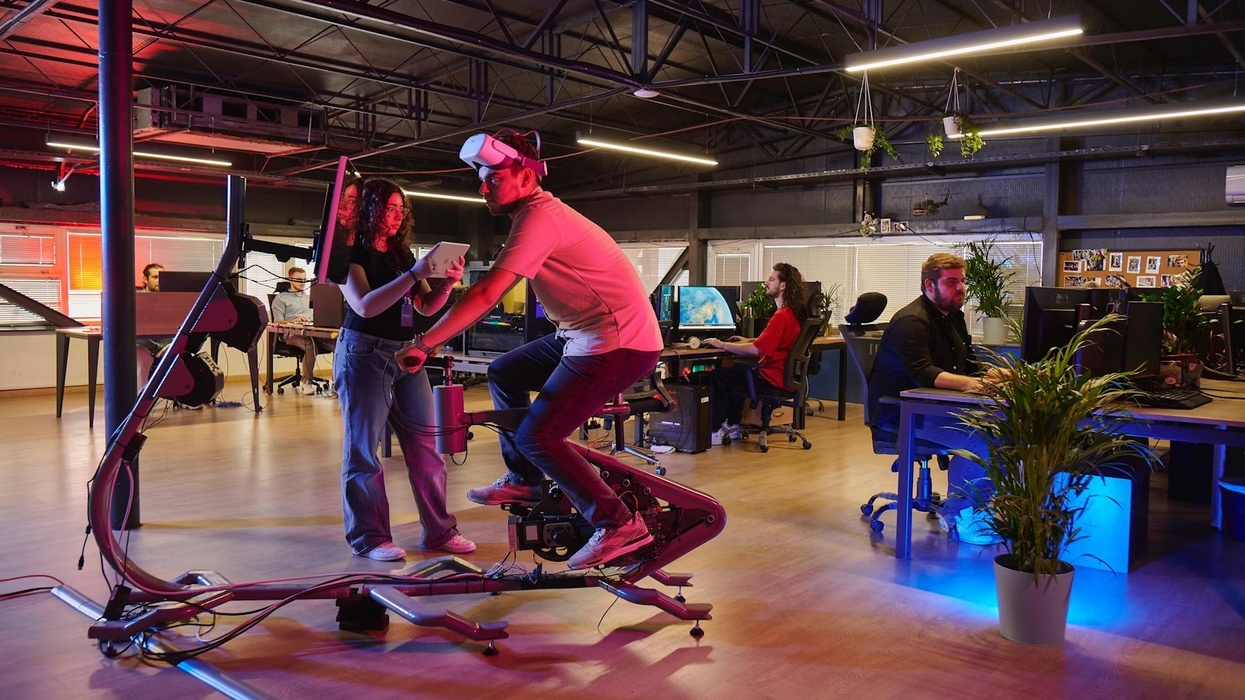 Person on Voyager Metabike in modern office, coworkers at desks.