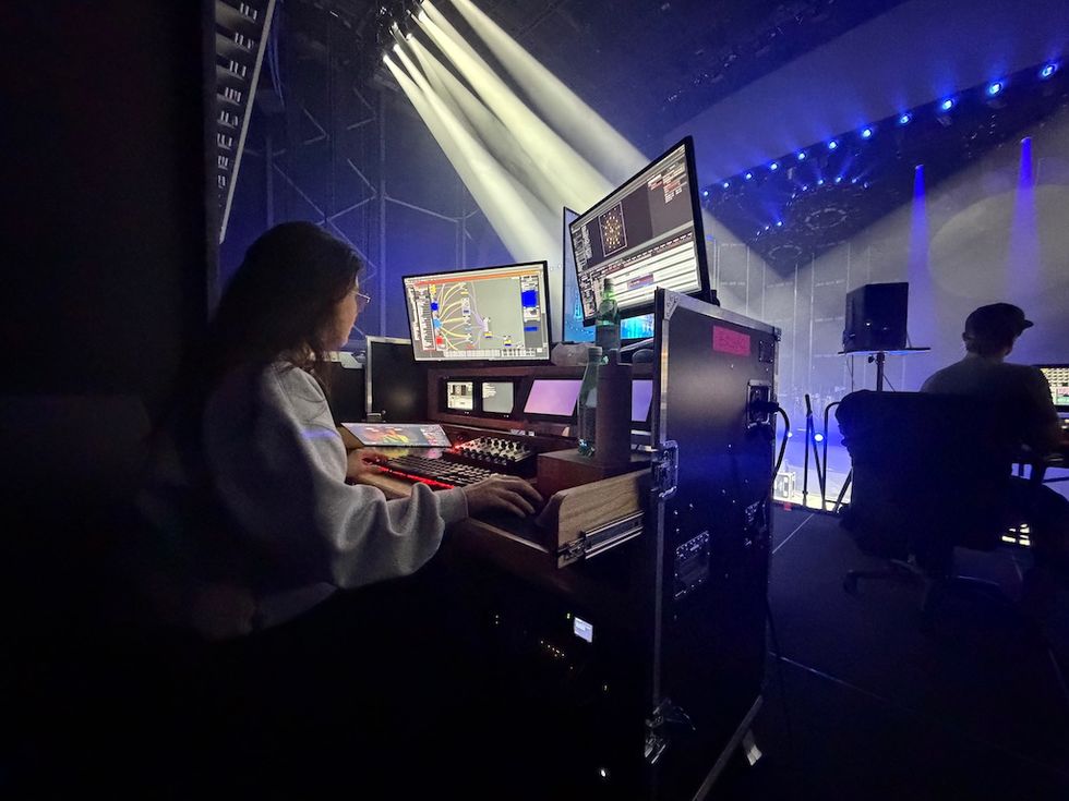 Person operating lighting control board in a dark theater.