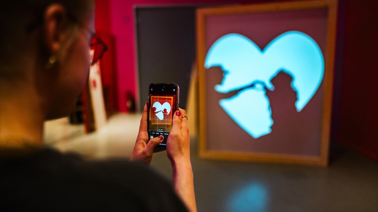 Person photographing heart-shaped silhouette with phone during About Love exhibition, Universum Bremen
