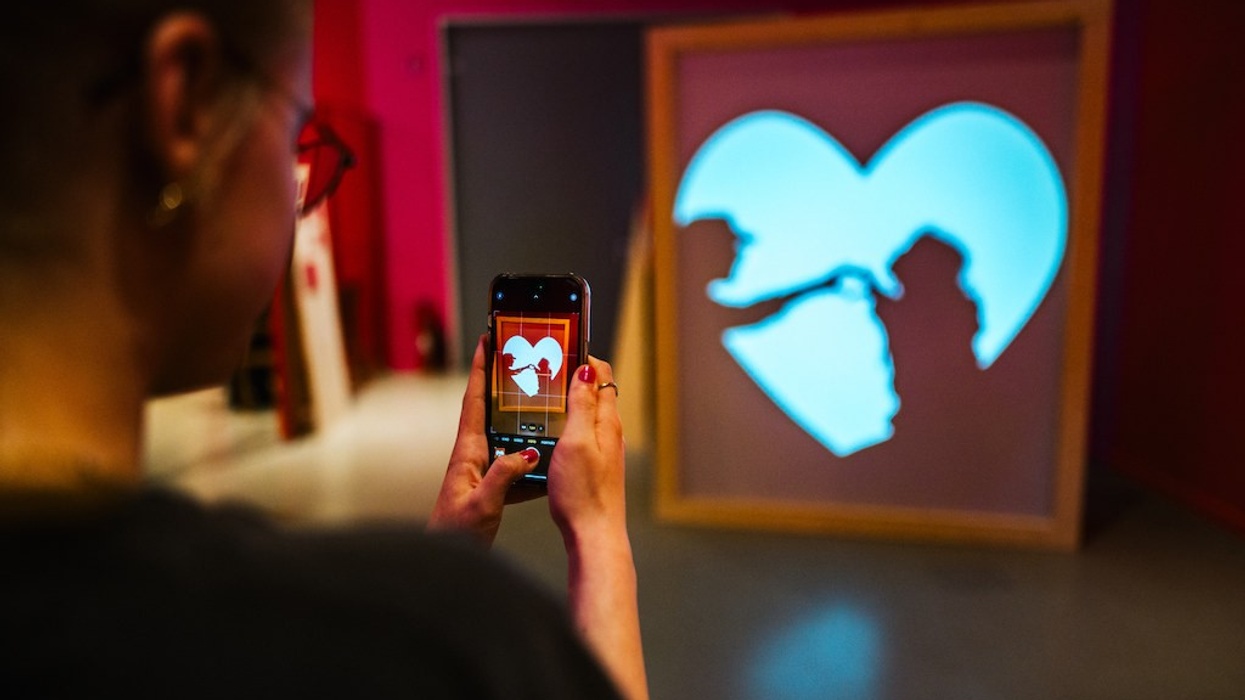 Person photographing heart-shaped silhouette with phone during About Love exhibition, Universum Bremen