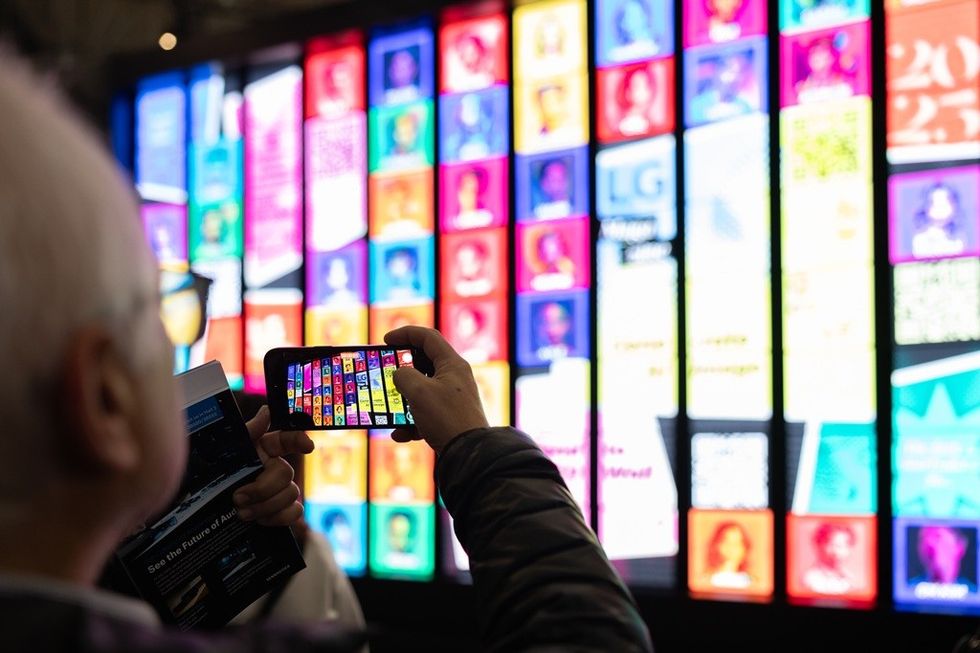 Person photographs a vibrant, multi-colored digital display with a smartphone.