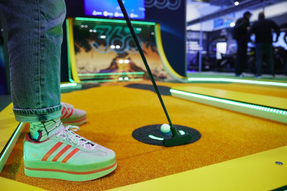 Person playing mini-golf in colorful sneakers on a vibrant course.