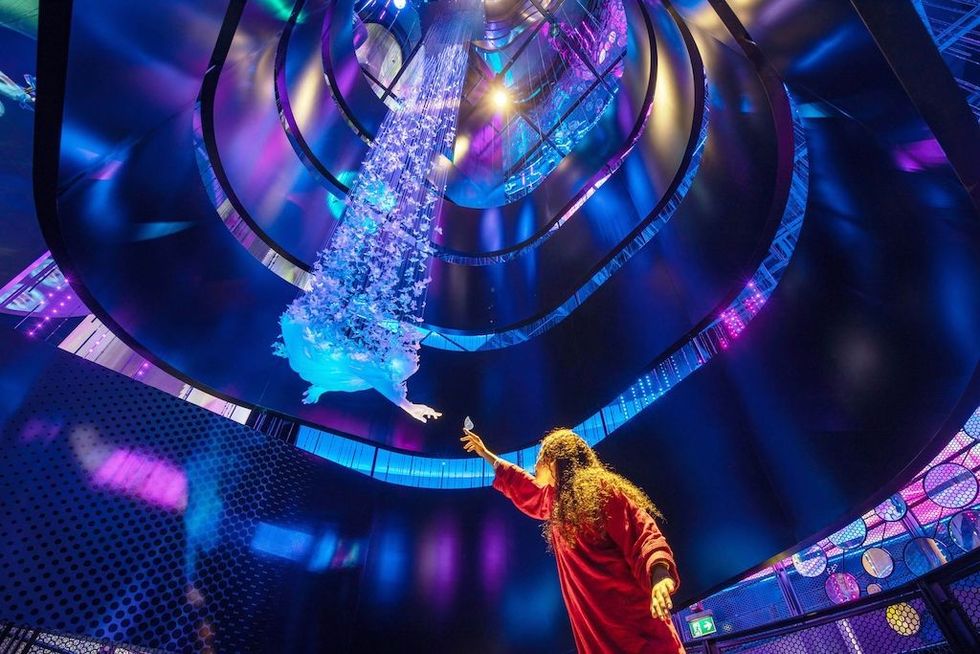 Person reaching toward a flying figure in a vibrant, multicolored spiraling space.