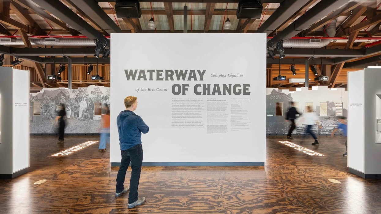 Person reading "Waterway of Change" exhibit text on a large display in a museum.