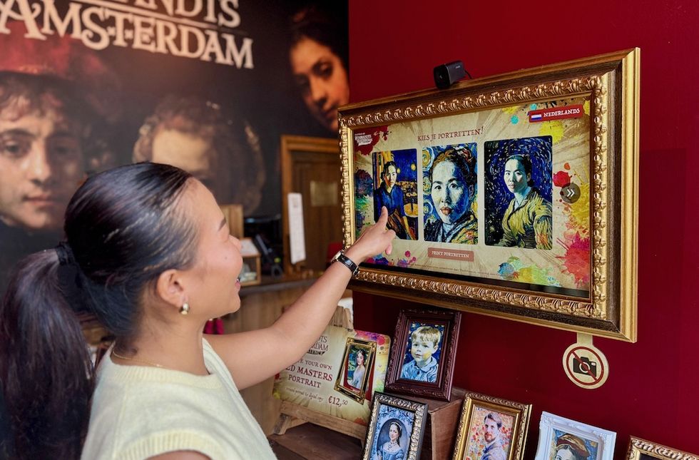Person selecting digital portraits on an interactive screen in a gallery setting.