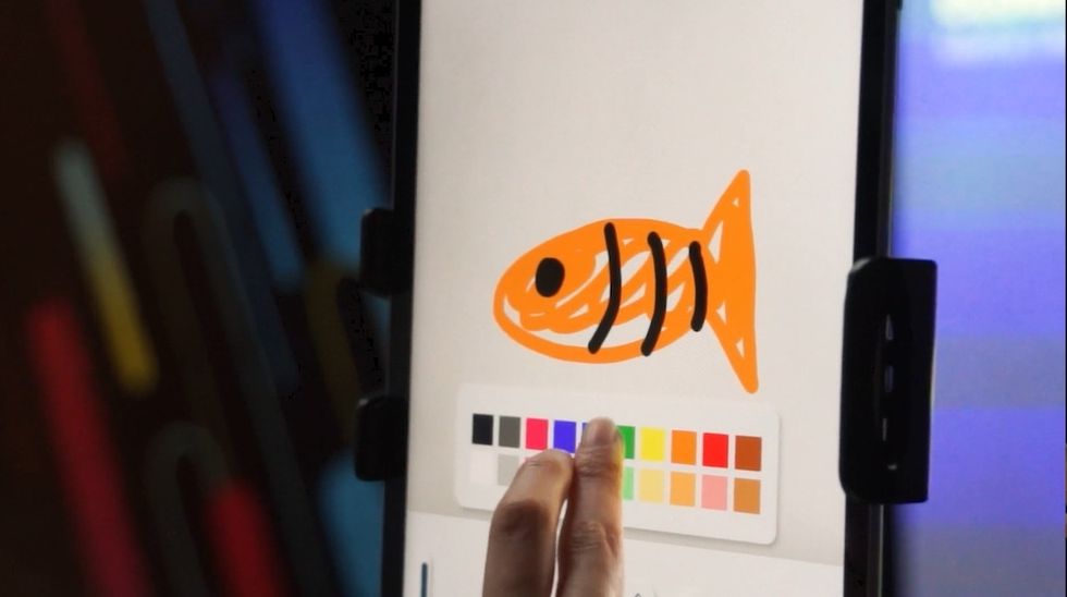 Person selects colors while drawing an orange fish on a tablet, Magic Painter