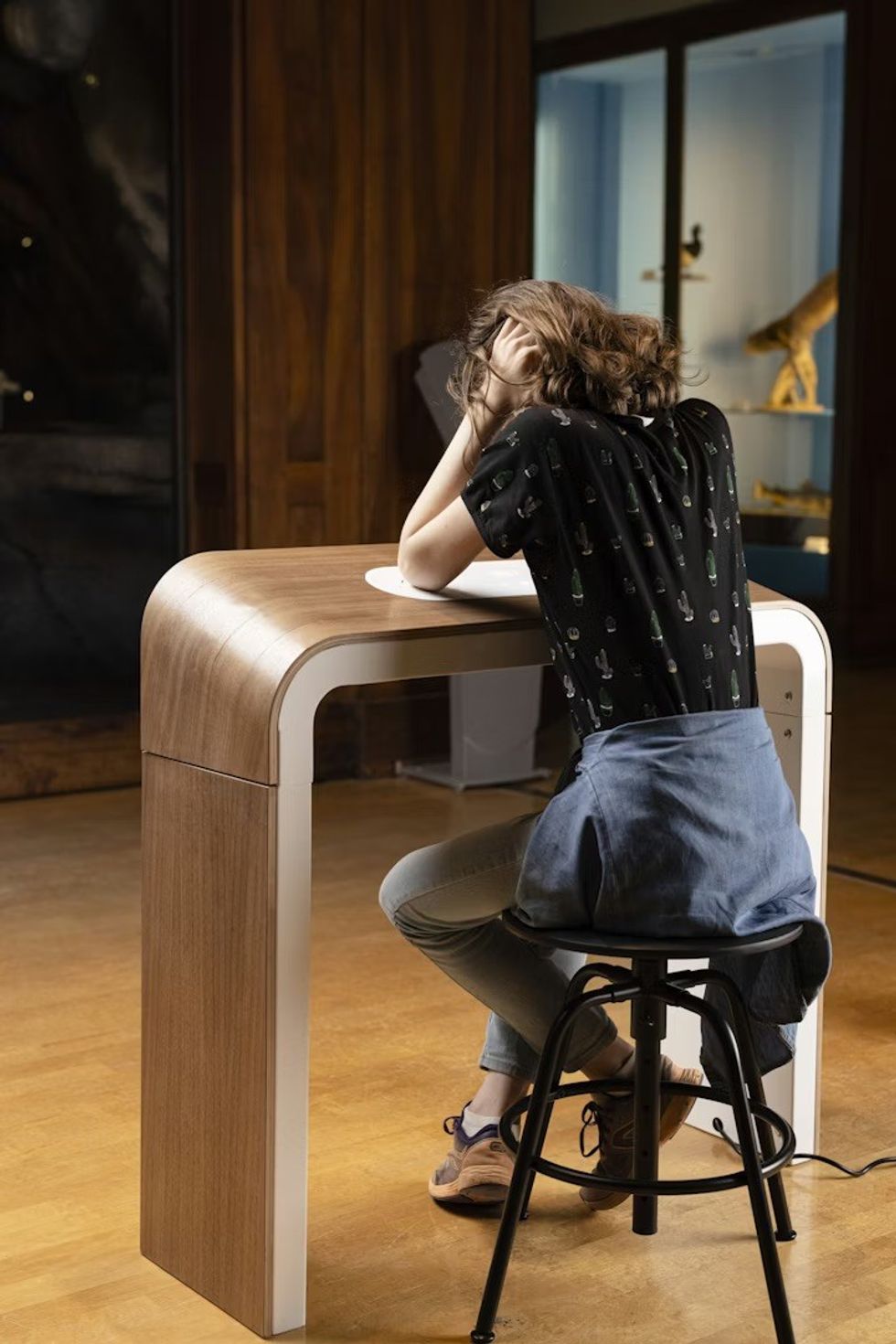 Person sitting at a Losonnante device , head in hands, in a dimly-lit room.