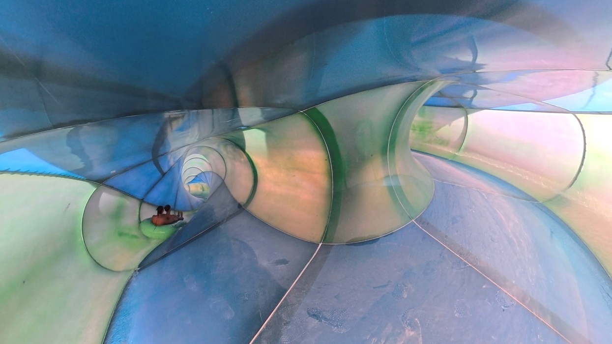 Person sliding inside a colourful, twisting water slide named Helix Twist