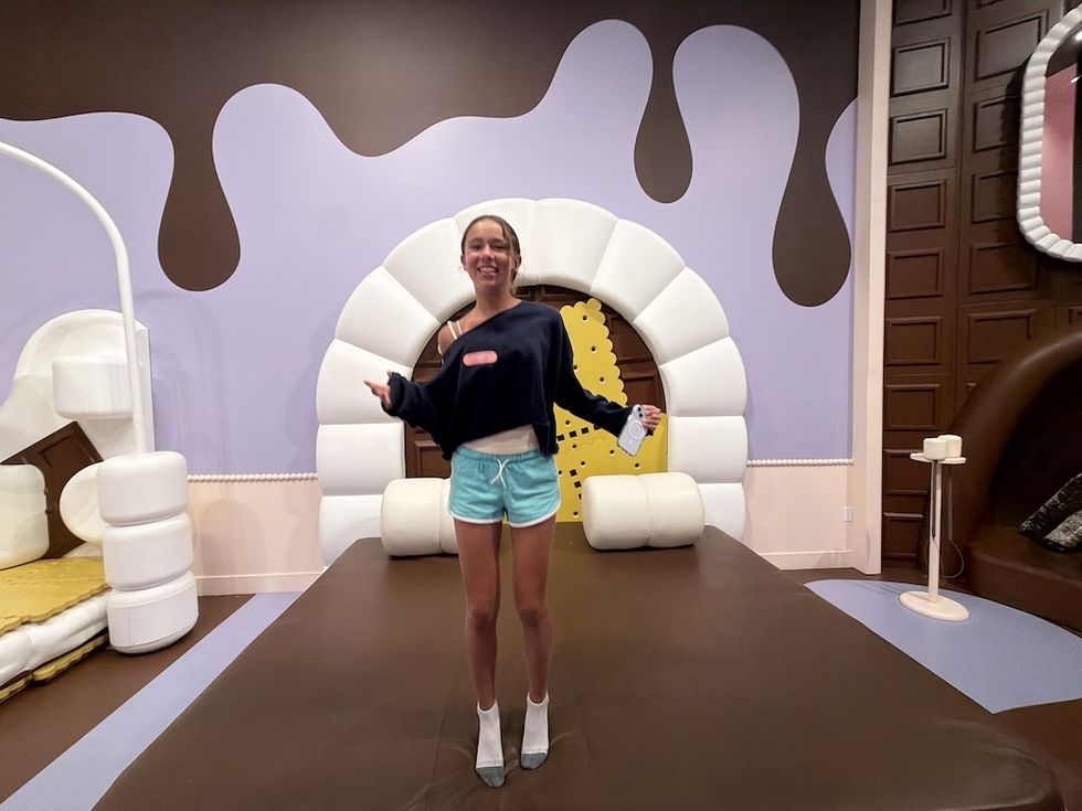 Person standing in a chocolate-themed room with playful decor at Museum of Ice Cream
