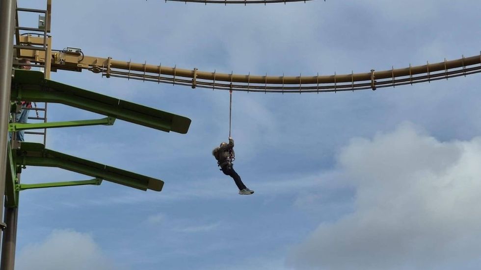 Person suspended on a zip line against a cloudy sky background at Universe Science Park.