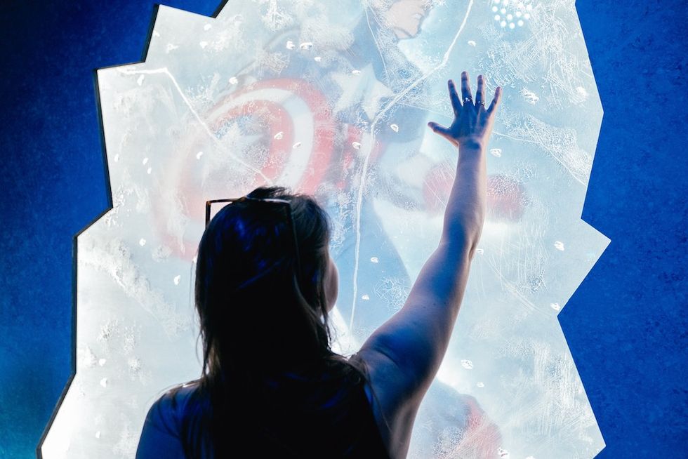 Person touching a frosted glass with a superhero image behind it.