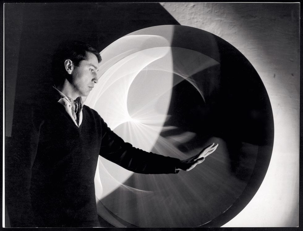 Person touching a large, abstract circular artwork with light and shadow effects.