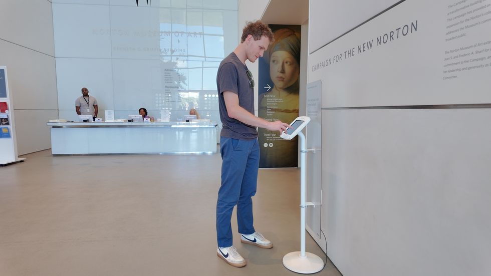 Person using a display stand in a modern museum lobby.