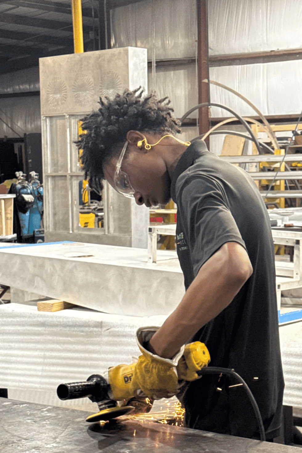 Person using an angle grinder, creating sparks in a workshop.
