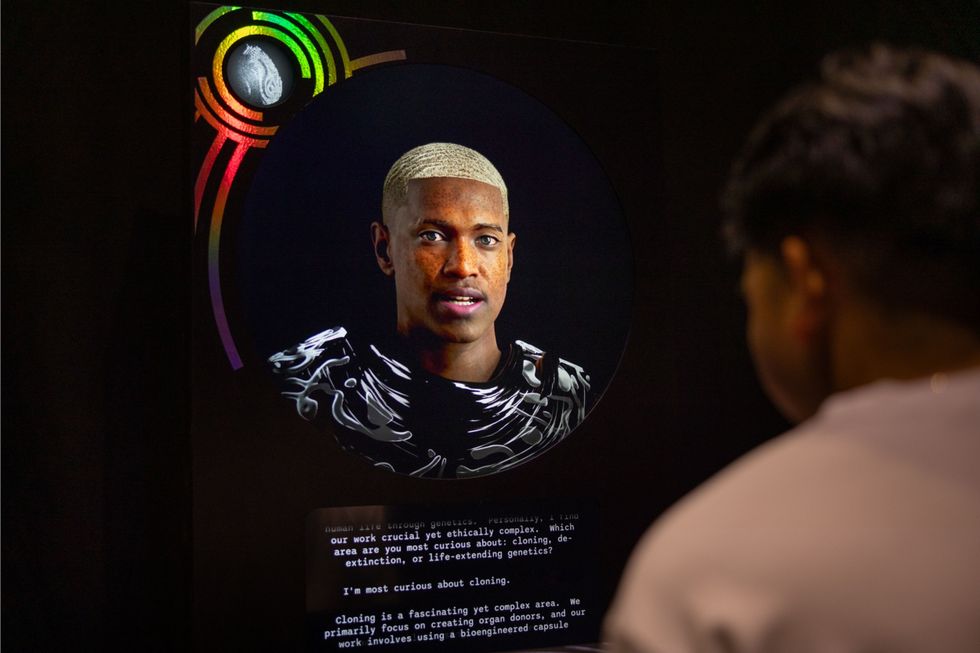 Person viewing a digital display with a futuristic design and text about cloning.