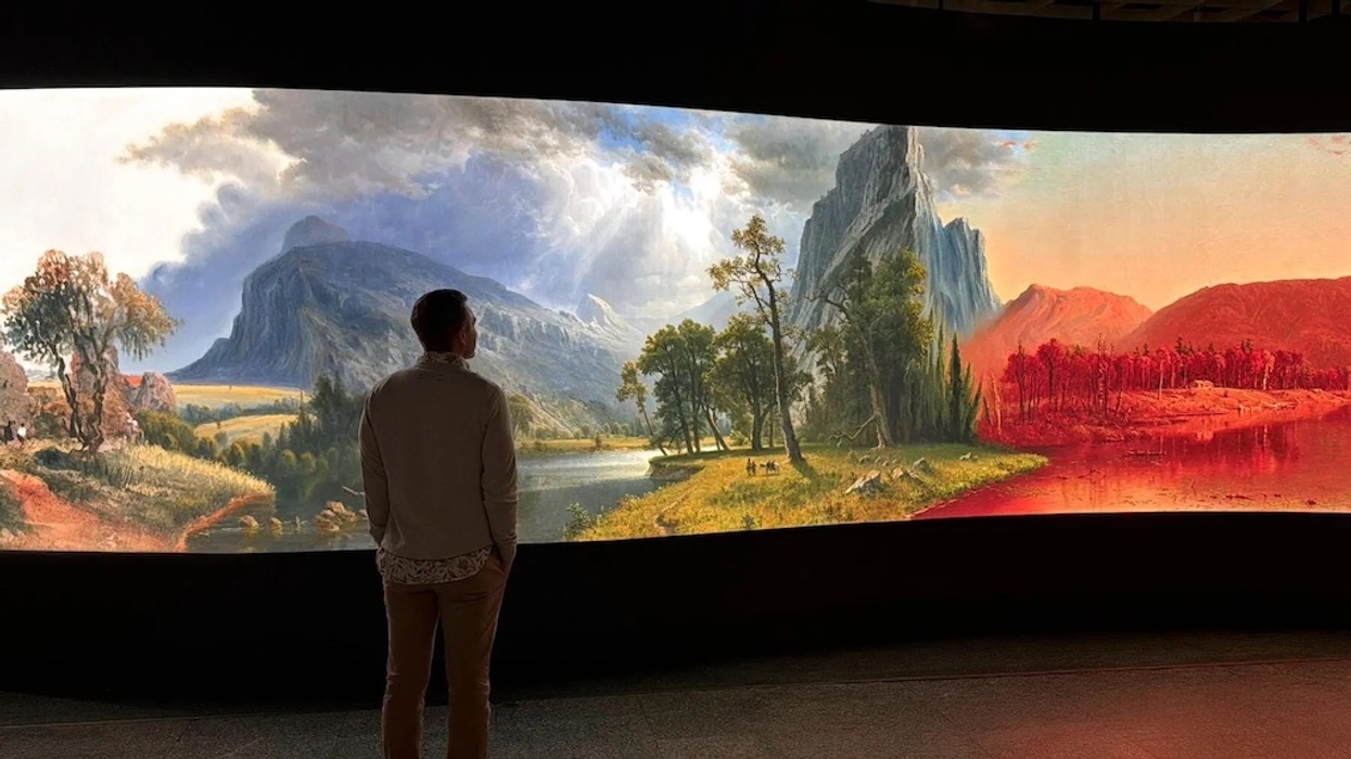 Person viewing a large, colorful landscape painting in a gallery.