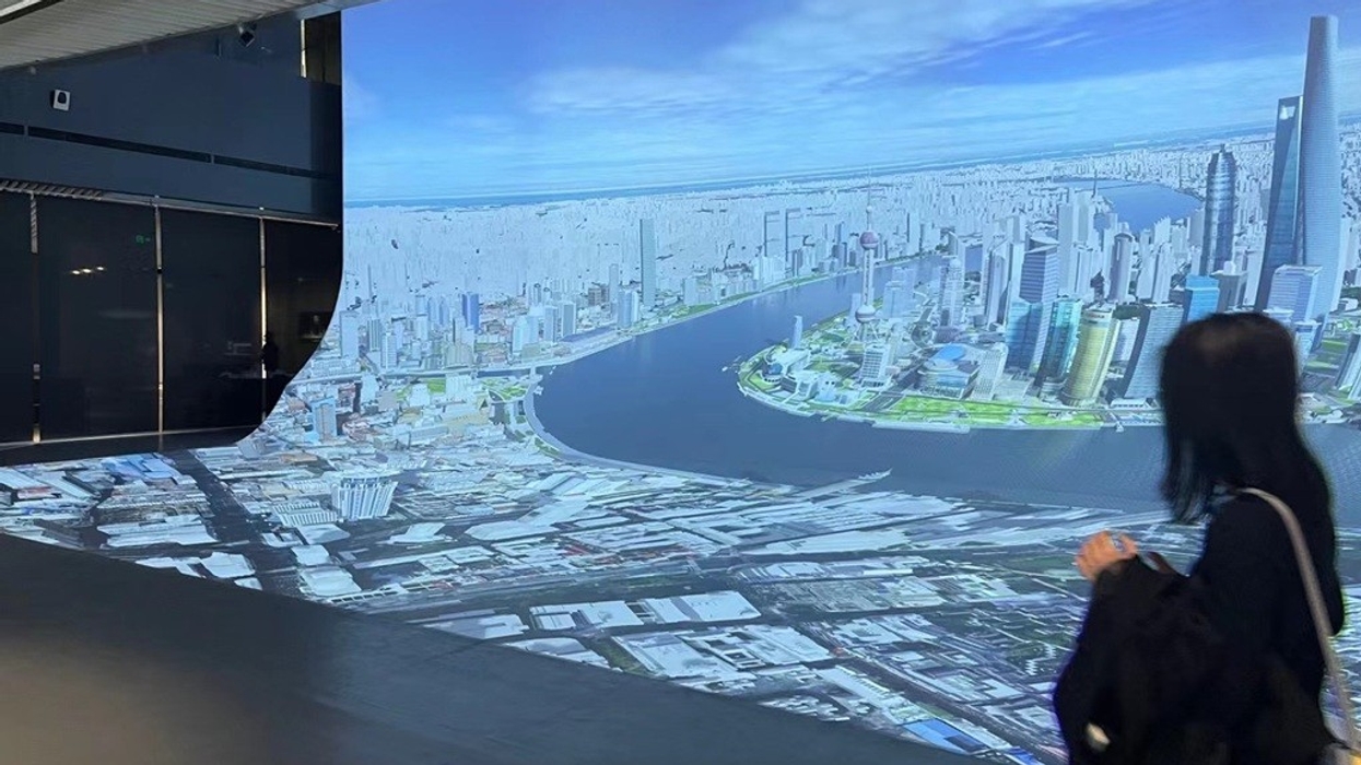 Person viewing a large digital cityscape display in an exhibition hall, the Digital Twin at SUPEC Shanghai