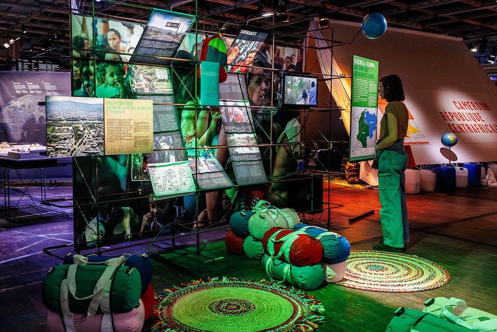 Person viewing an informative exhibit with colorful posters and rolled sleeping bags.