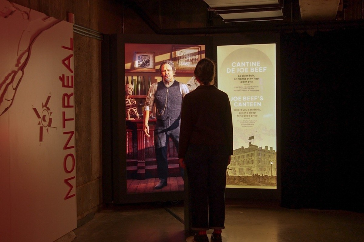 Person viewing exhibit display about Joe Beef in Montréal-themed space.