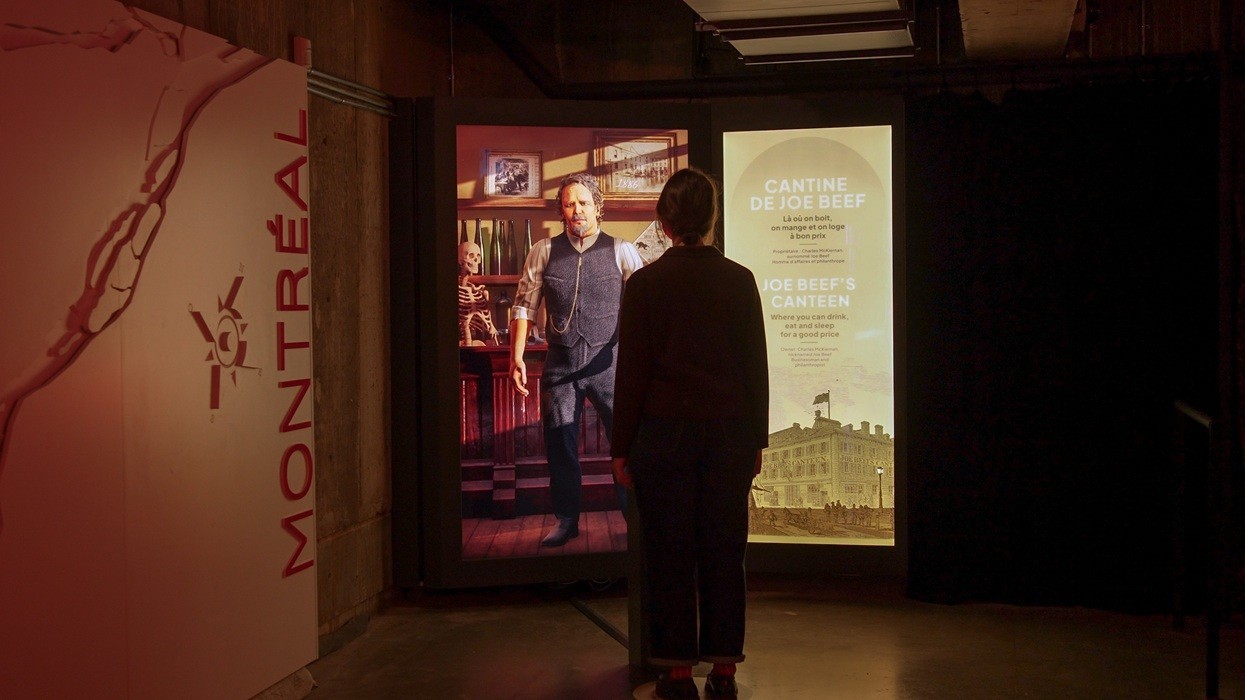 Person viewing exhibit display about Joe Beef in Montréal-themed space.