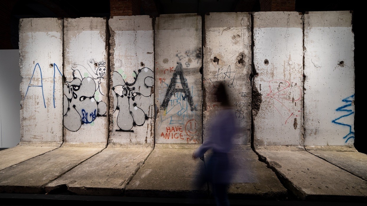 Person walking past graffiti-covered concrete wall panels.