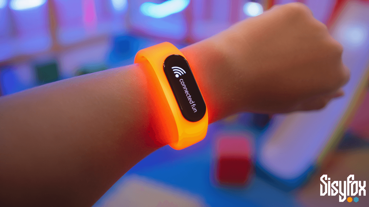 Person wearing an orange smart wristband from SisyFox with "connected fun" showing on display.