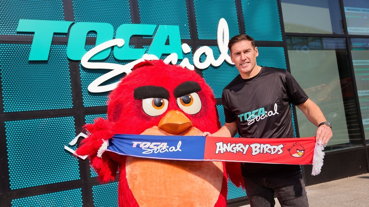 Person with Angry Birds mascot holding a "TOCA Social" scarf outside the venue.