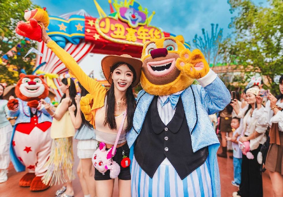 Person with Boonie Bear mascot at amusement park entrance.