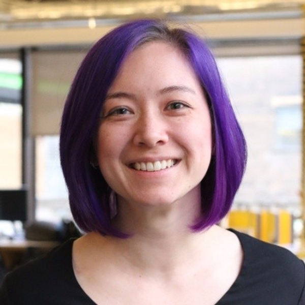 Person with short purple hair smiling indoors.