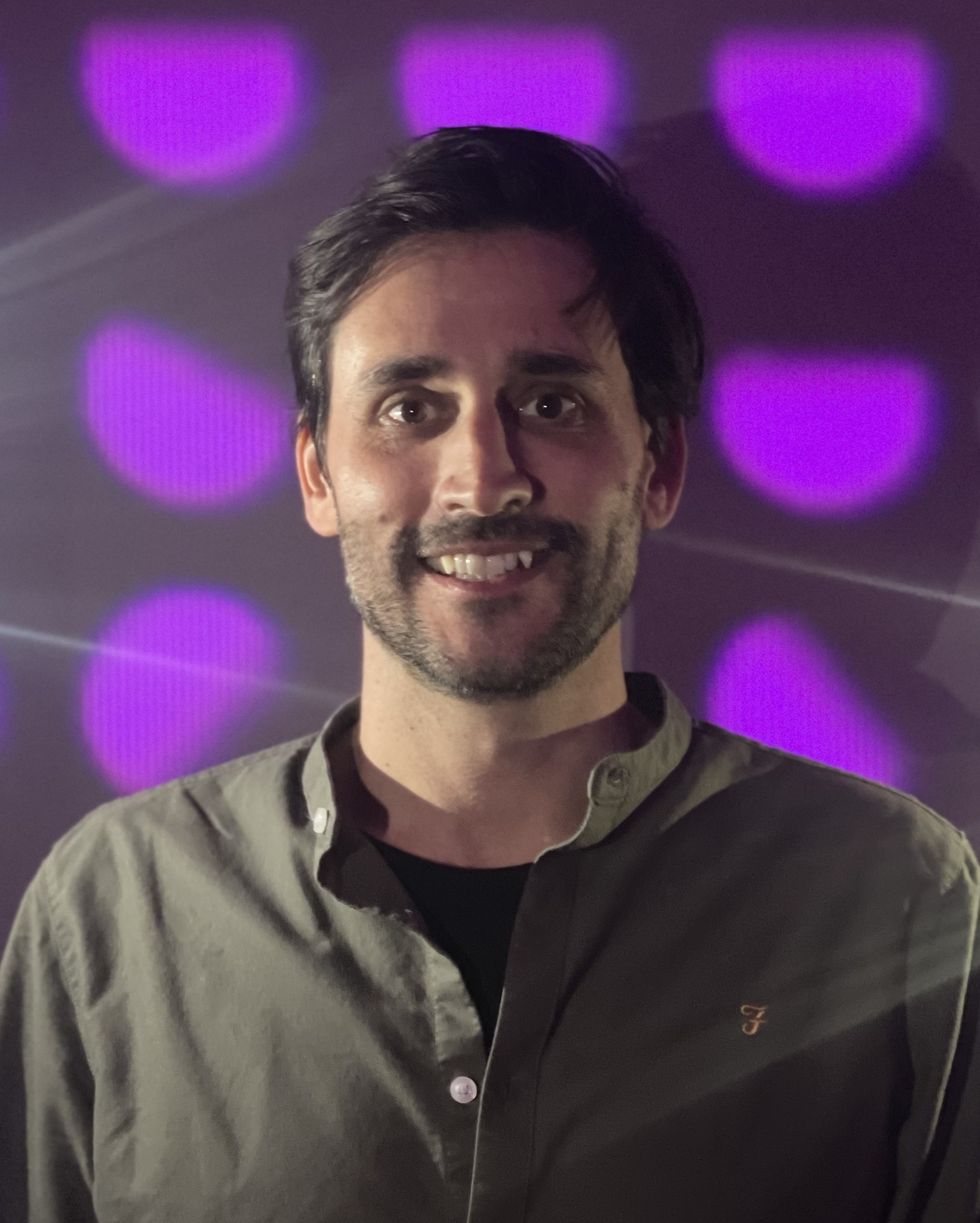 Philippe Trawnika in a dark shirt against a purple polka dot background.
