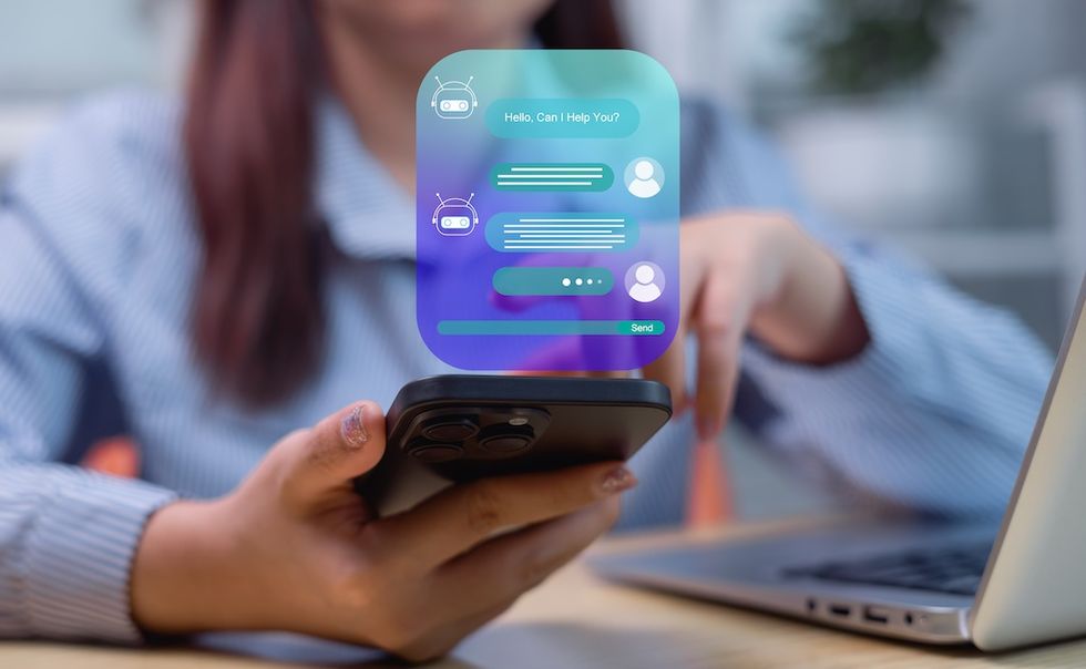 Phone displaying chatbot interface next to laptop.