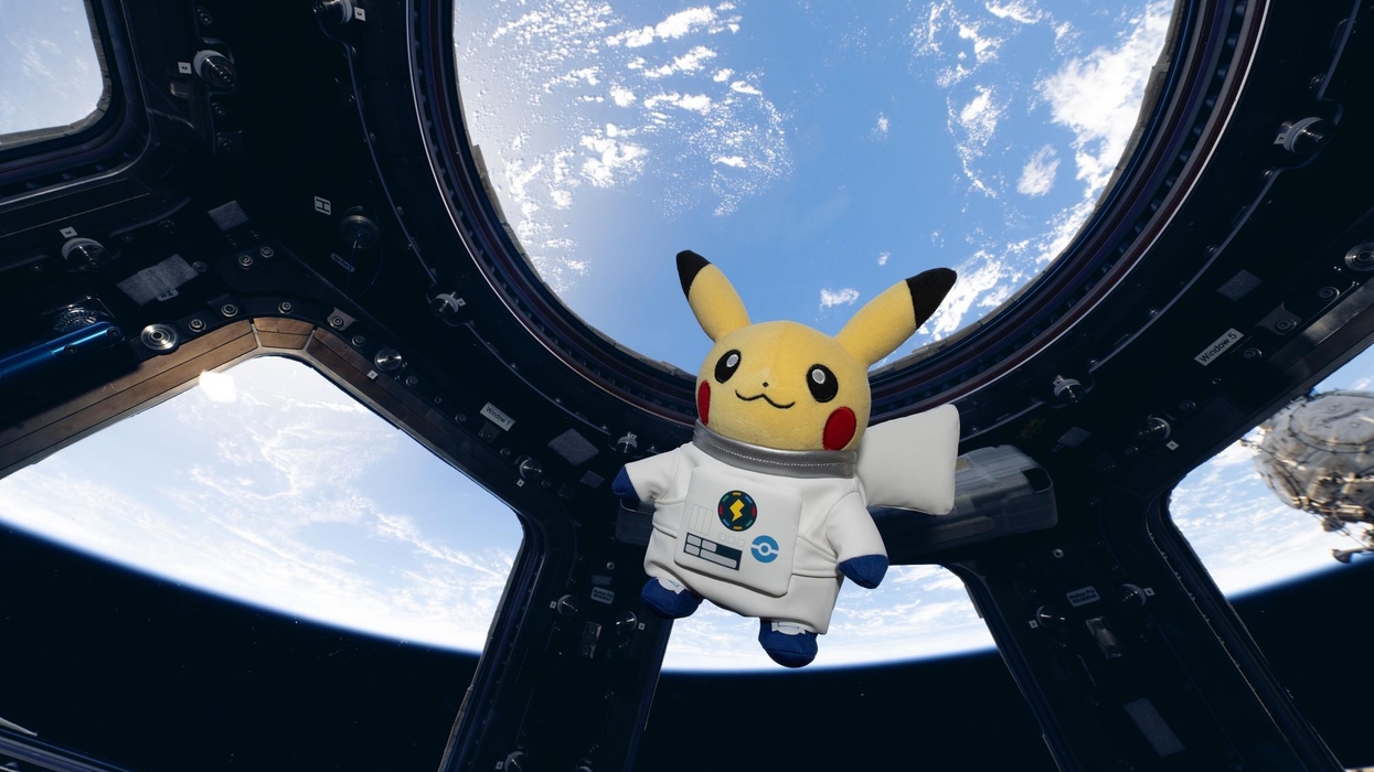 Pikachu plush in astronaut suit floating inside a space station with Earth in the background.