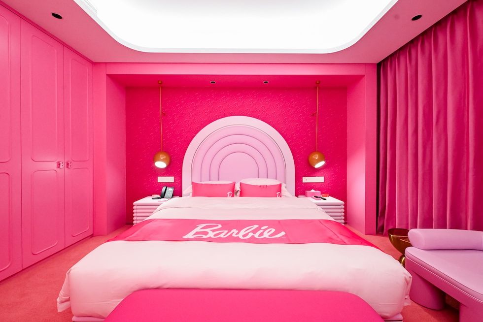 Pink Barbie-themed bedroom with arch headboard and gold hanging lamps.