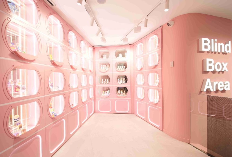 Pink room with illuminated cubbies displaying assorted blind box toys at Miniso Land