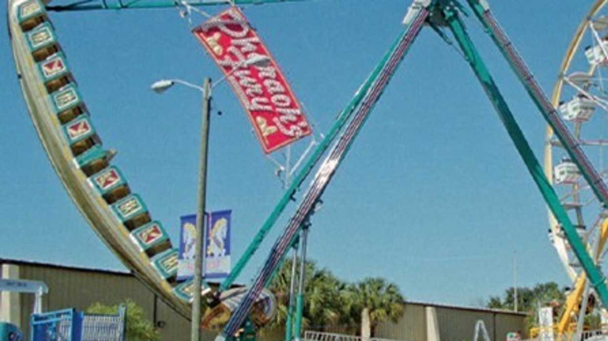 Pirate ship amusement ride with a Ferris wheel in the background under a clear blue sky.
