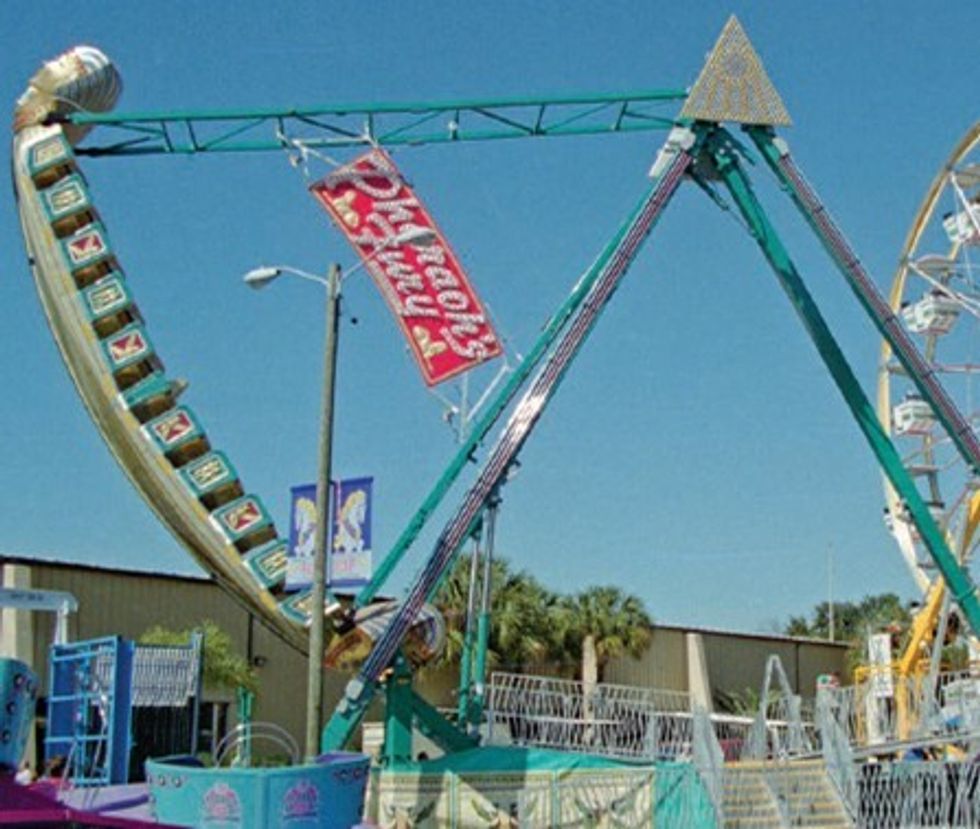 Pirate ship amusement ride with a Ferris wheel in the background under a clear blue sky.