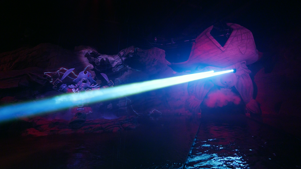 Pirate-themed ride with glowing laser eye and misty, colorful lighting effects.