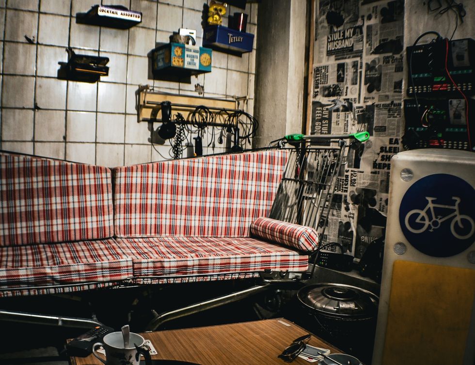 Plaid couch in eclectic room with newspaper wall and vintage decor at Absurd City