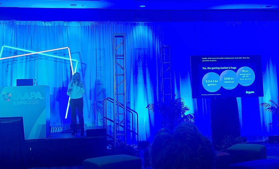 Presenter on stage at IAAPA Expo 2025, discussing gaming market statistics.