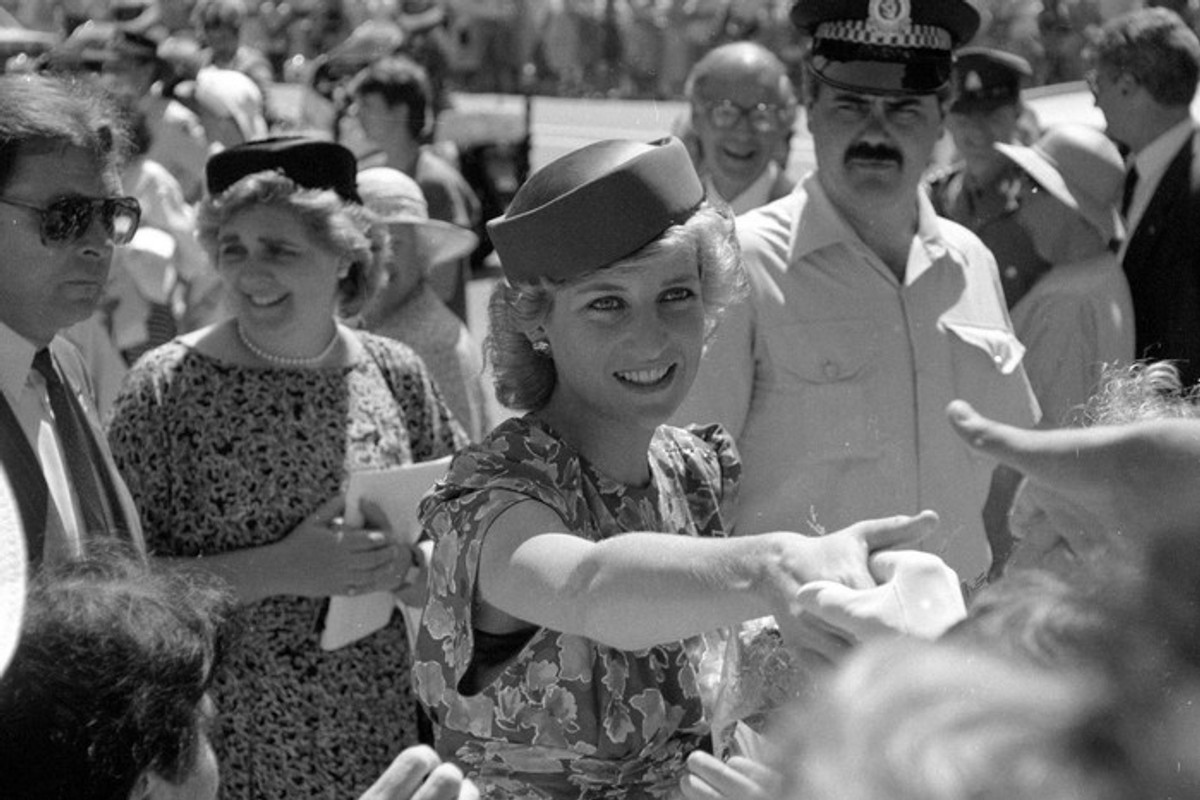 Princess Diana in a floral dress greeting a crowd, with police and bystanders nearby.