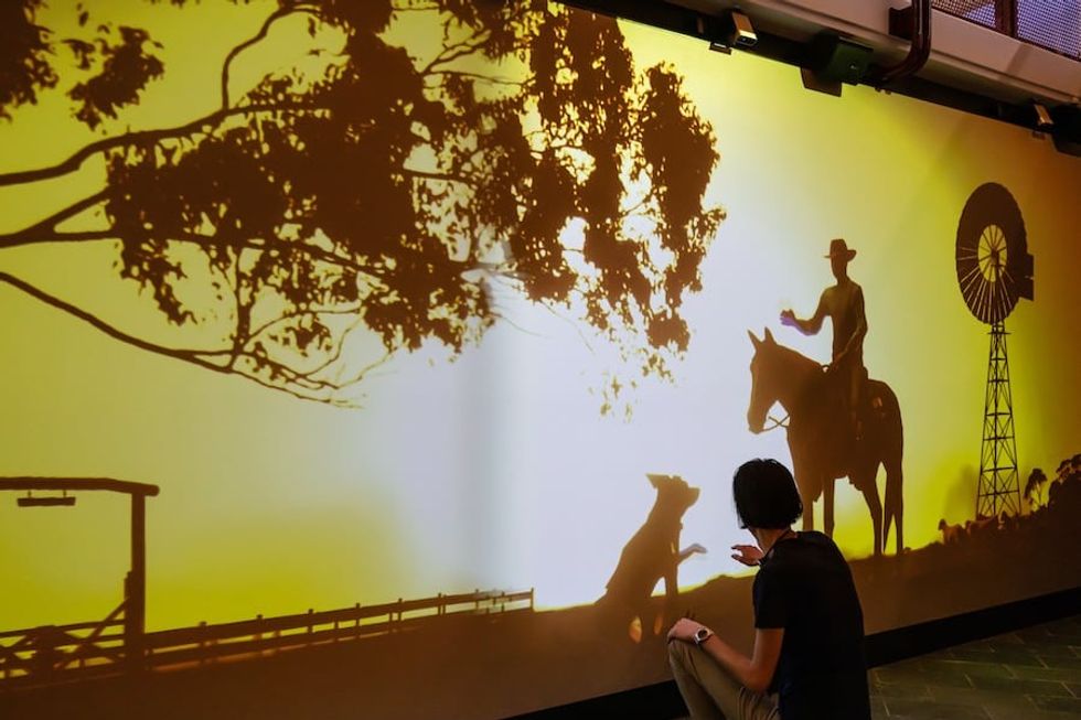 Projection mapped sunset scene of a cattle farmer and a dog