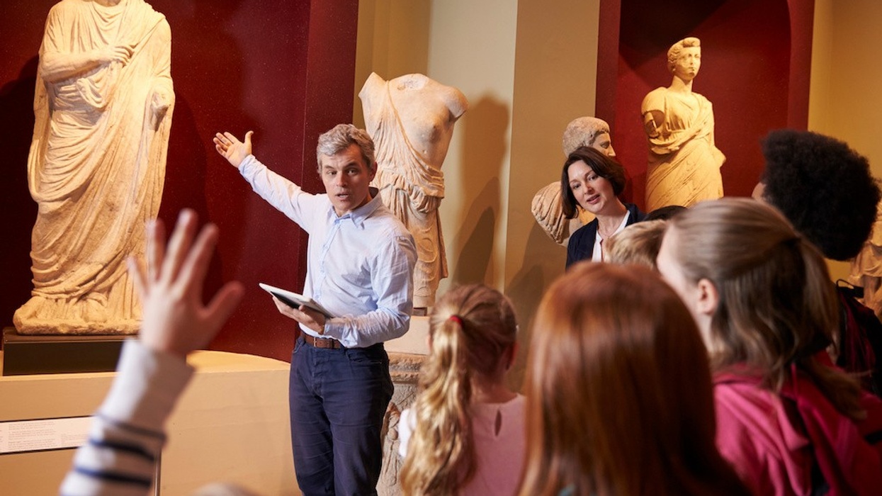 Pupils And Teacher On School Field Trip To Museum With Guide