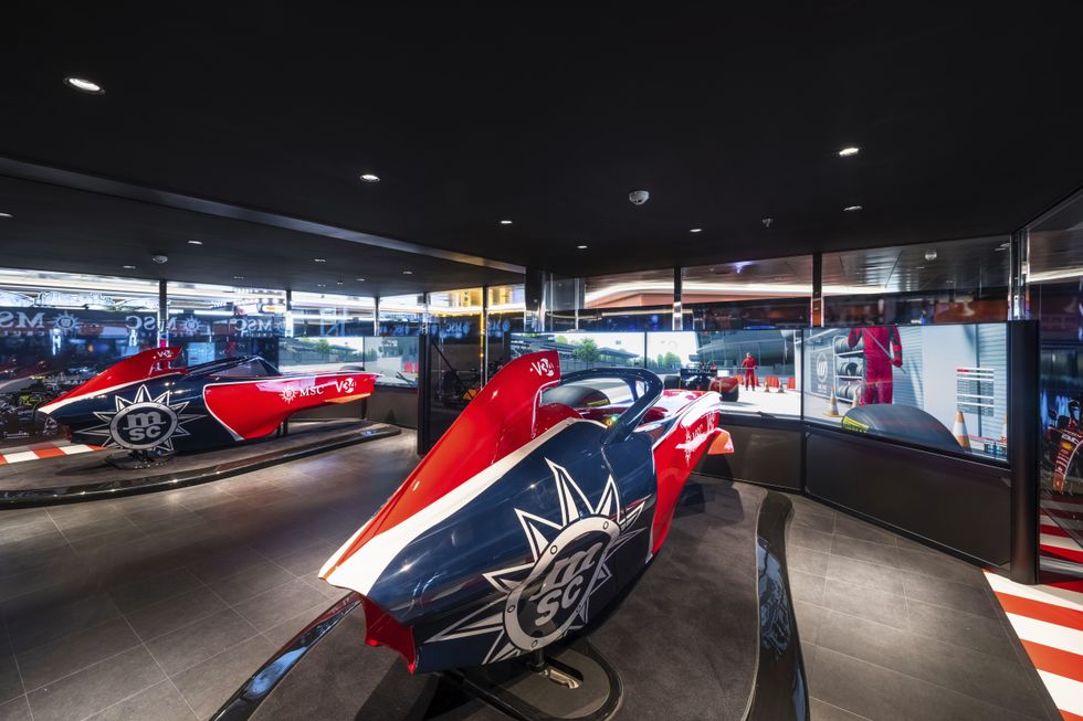 Racing simulators in a sleek, modern room with vibrant lighting and floor-to-ceiling windows on MSC World Asia.