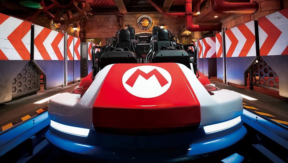 Red and white Mario-themed ride car in a themed amusement park setting.