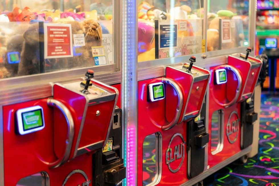 Red arcade claw machines with joysticks and plush toys inside & Semnox card readers