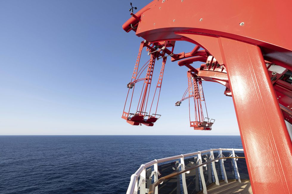 Red ride structure over ocean on a cruise ship called MSC World Asia, with clear blue sky.