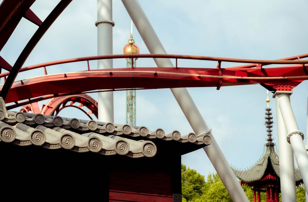 Red roller coaster track above traditional Asian-style roof at Tivoli Gardens