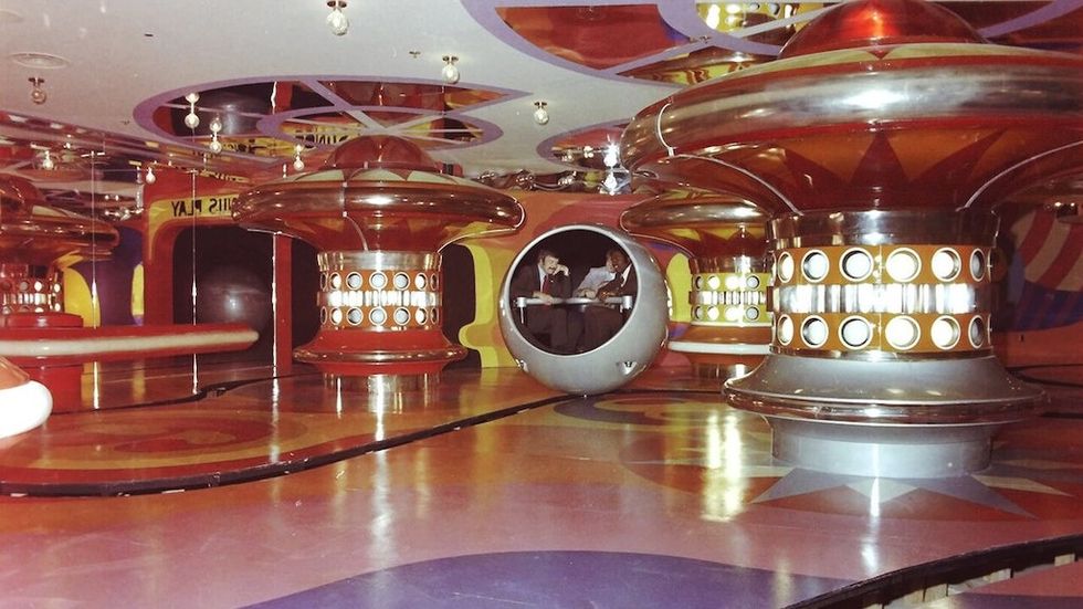 Retro futuristic lounge with circular booths and vibrant colors, The World of Sid and Marty Krofft