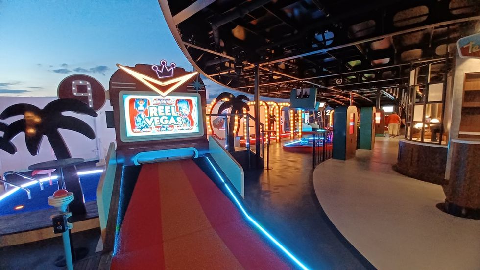 Retro mini golf from 360Golf with vibrant neon lights and palm tree decorations at sunset.